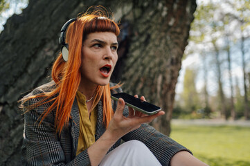 Businesswoman recording voice message using smartphone app in park