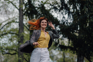 Happy businesswoman listening music with headphones and dancing in the park