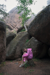 Woman in the raincoat the taiga forest and rocks of the Stolby nature reserve park, Krasnoyarsk, Russia