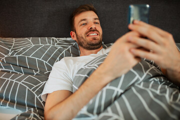 Man lying in the bed and scrolling before sleep