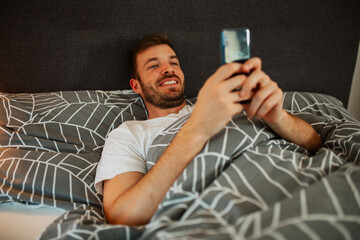 Man lying in the bed and scrolling before sleep