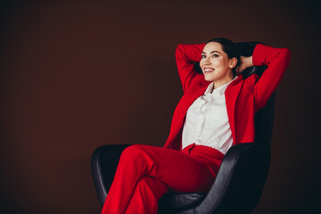 Beautiful Attractive Confident Businesswoman Relaxing in a Chair in Stylish Red Formal Suit