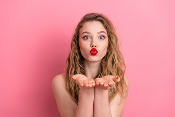 Young fashionable woman blowing a kiss on pink background showing affection