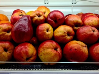 Red pears stacked in bulk at the market. Fresh ripe pears with smooth red skin and natural texture,...