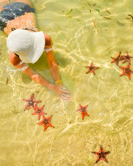 Woman tourist visit star fish beach pick starfish in famous tropical Koh Rong island, Cambodia....