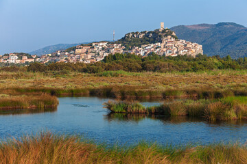 Historic fortified town of Posada perched above green wetlands in Sardinia Italy