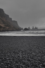 Dramatic landscape of black sand beach and cliffs and rocks by the sea