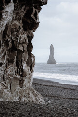Dramatic landscape of black sand beach and cliffs and rocks by the sea