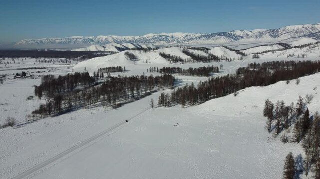 Drone footage of snowy mountains, valleys, and forests in Ust-Koksa, Altai Republic, Russia, under clear skies, showing the remote region&rsquo;s beauty during winter.