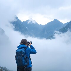 A woman stands on a rocky outcrop, capturing stunning mountain landscapes with her camera, surrounded by lush greenery and a clear blue sky.