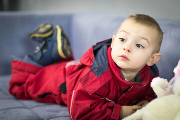 Happy Two-year baby lies on a sofa in a Red Jumpsuit