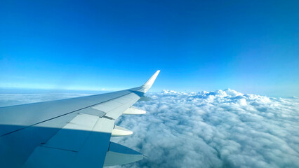 Obraz premium Airplane wing above clouds.View from airplane window a blue sky and clouds.
