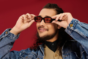 Handsome young man enjoying a moment with stylish sunglasses against a vibrant backdrop
