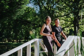 Fototapeta premium Smiling couple enjoy quality time outdoors, leaning on a wooden bridge in a lush green park, showcasing happiness and a strong connection. The bright day enhances the cheerful and relaxed atmosphere.