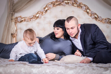 Dad and mom play with a son on the bed