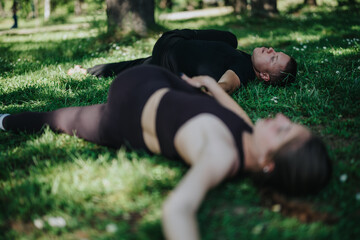 A pair of people lying peacefully on a grassy field surrounded by natural greenery. The photograph...
