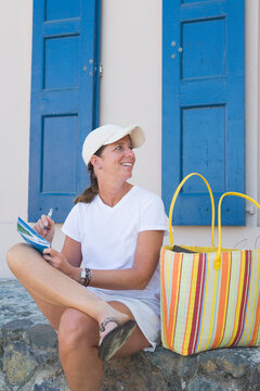 Smiling woman on vacation writing postcard