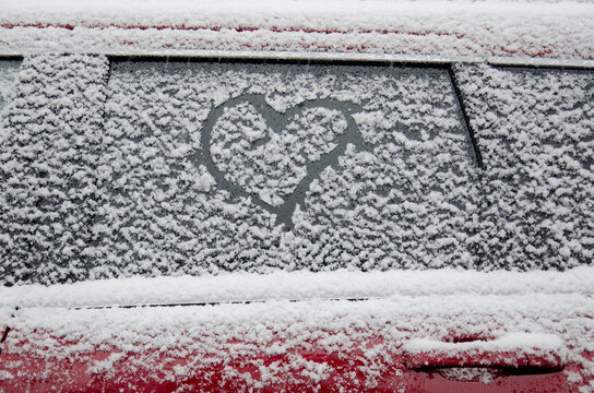 Heart shape drawn on snow covered car window
