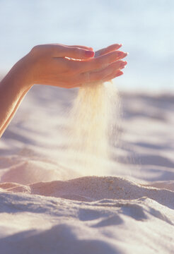 Beach sand slipping through woman's hands