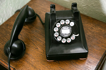 Black antique rotary phone on wooden table