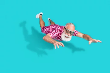 Fototapete Full body photo of attractive senior bearded man falling parachutist dressed stylish pink leopard print clothes isolated on cyan background © deagreez