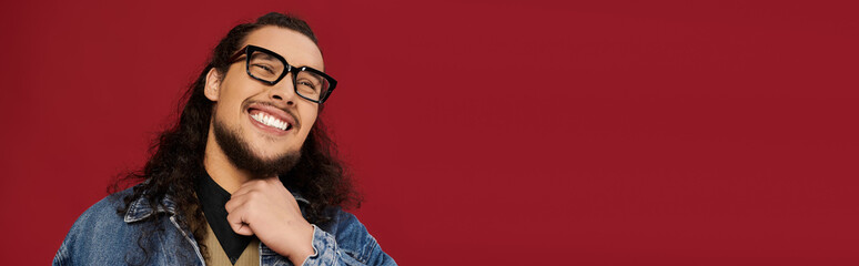 Handsome young man with beard smiles confidently against a vibrant red backdrop
