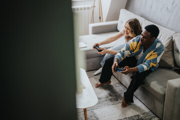 Diverse couple sitting on a cozy couch in a modern living room, bonding and having fun while playing video games, evoking joy and togetherness.