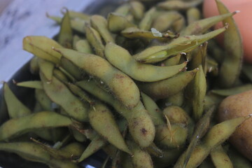 Boiled edamame is placed in a container and will be processed into a fruit salad.