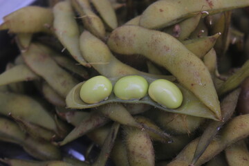 Boiled edamame is placed in a container and will be processed into a fruit salad.