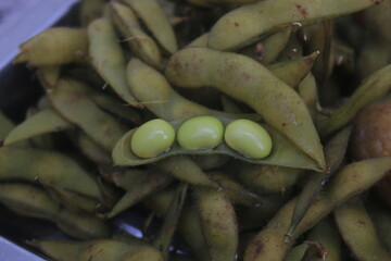 Boiled edamame is placed in a container and will be processed into a fruit salad.
