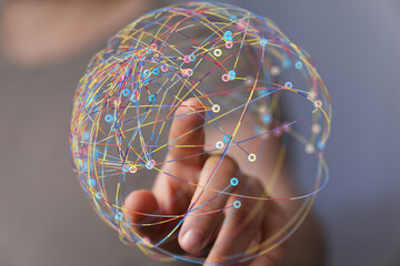 Abstract image of a hand interacting with a colorful global network sphere.  Represents connection,...