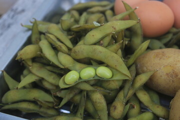 Boiled edamame is placed in a container and will be processed into a fruit salad.