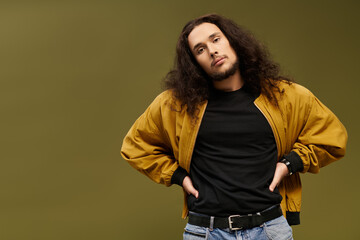 Handsome young bearded man poses confidently in stylish casual outfit against a bold backdrop
