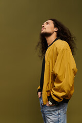 Young bearded man in stylish jacket gazes thoughtfully at the ceiling in modern studio space