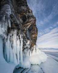 Majestic ice formations on a rocky cliff by a frozen lake.