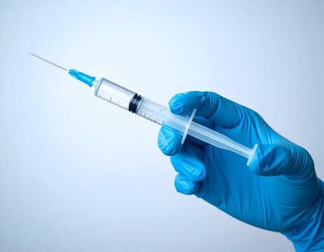 Hand in blue glove holding a medical syringe with a needle. Ideal for healthcare, vaccination, treatment, disease prevention, scientific research, and public health campaigns.