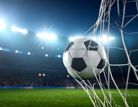 Soccer ball strikes the goal net against a brightly lit stadium background, capturing the decisive moment of a score in an exciting football match.