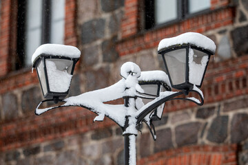 Vintage Street Lamp Covered in Snow During Winter Storm Near Brick Stone Building