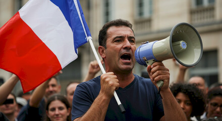 Man speaking into megaphone while holding French flag at protest  