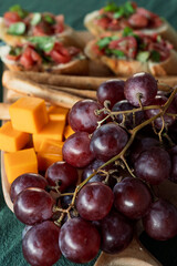 Close-up of grapes, cheddar cheese, and bruschetta on rustic serving board
