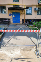 Asphalt repair with warning tape around the entrance residential building.