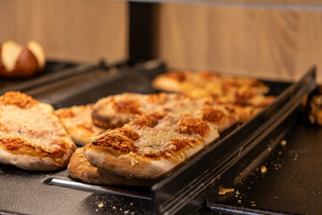 Freshly baked small pizzas with melted cheese and savory tomato sauce displayed on a buffet tray,...