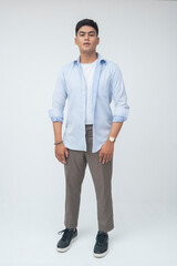 Filipino Gen Z male stands confidently with relaxed posture in full body shot, wearing casual wear in a minimalist studio with neutral facial expression.