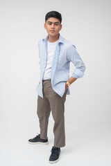 Confident Southeast Asian man poses with hands in pockets while leaning forward slightly, wearing...