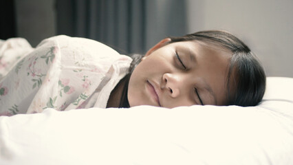 A girl is sleeping on a bed with plain white sheets in a bedroom at home. Cute close-up face Sleep...