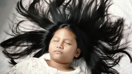 A girl is sleeping on a bed with plain white sheets in a bedroom at home. Cute close-up face Sleep...