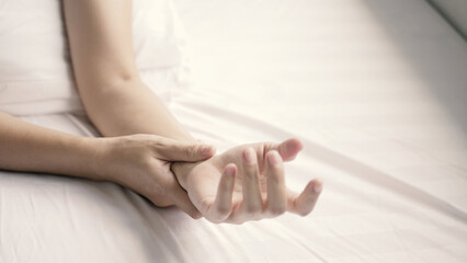 A beautiful woman has wrist pain from work for many days. She uses her other hand to gently massage...
