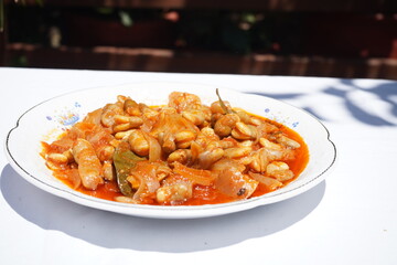 Side view of fresh broad beans (fava beans) cooked in a traditional Cretan tomato-based stew (giachni). This rustic Mediterranean dish showcases local produce, authentic flavors, and healthy eating 