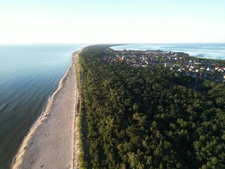 Stunning overhead view of coastal town with houses scattered along forest-covered peninsula beside...