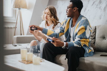 A diverse couple seated on a comfortable couch enjoying a video gaming session together in a...